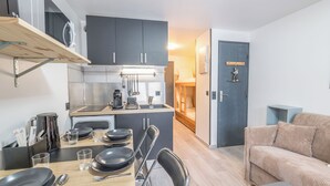 A compact kitchen with modern appliances, a dining area with a table set for two, and a cozy living space with a sofa. - Studio L'étoile des neiges - Welkeys (Demi-Quartier)