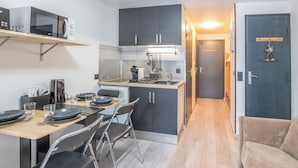 A compact kitchen with a dining area, a microwave, a coffee maker, and a small refrigerator. - Studio L'étoile des neiges - Welkeys (Demi-Quartier)