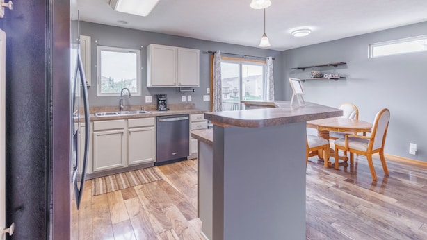 Una cocina moderna con una isla central, electrodomésticos integrados y un comedor con mobiliario de madera.