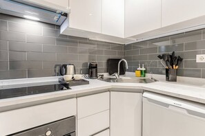 Eine moderne Küche mit grauen Fliesen, Geschirrspüler, Kaffeemaschine und Spüle.