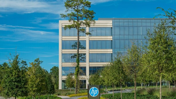 Um edifício moderno com céu claro, uma placa com o logotipo HP e um caminho que leva à entrada.