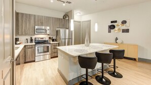 Uma cozinha moderna com eletrodomésticos de aço inoxidável, uma ilha central com banquetas e decoração minimalista.