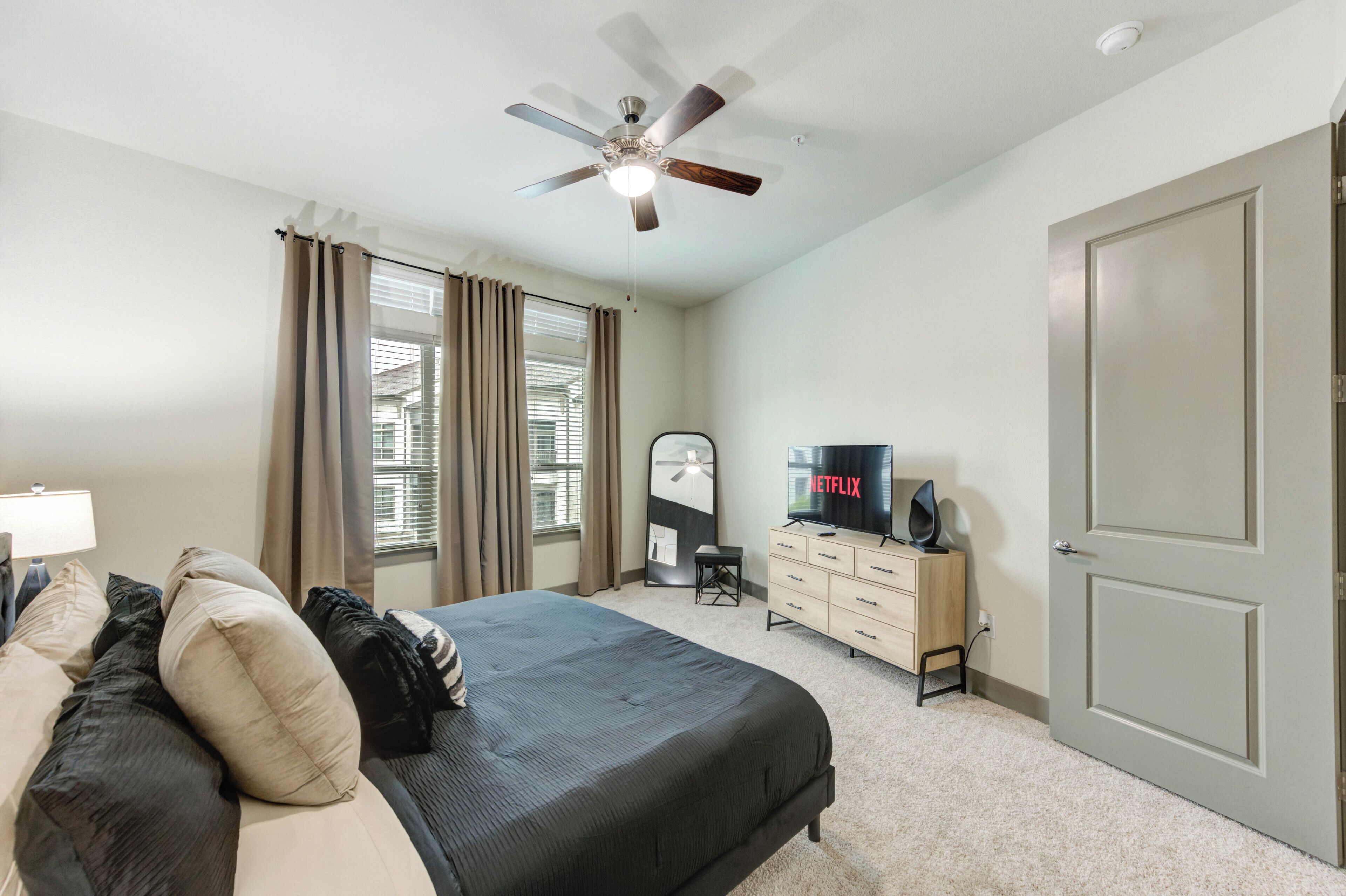 A bedroom with a bed, a dresser, a television, and a ceiling fan.