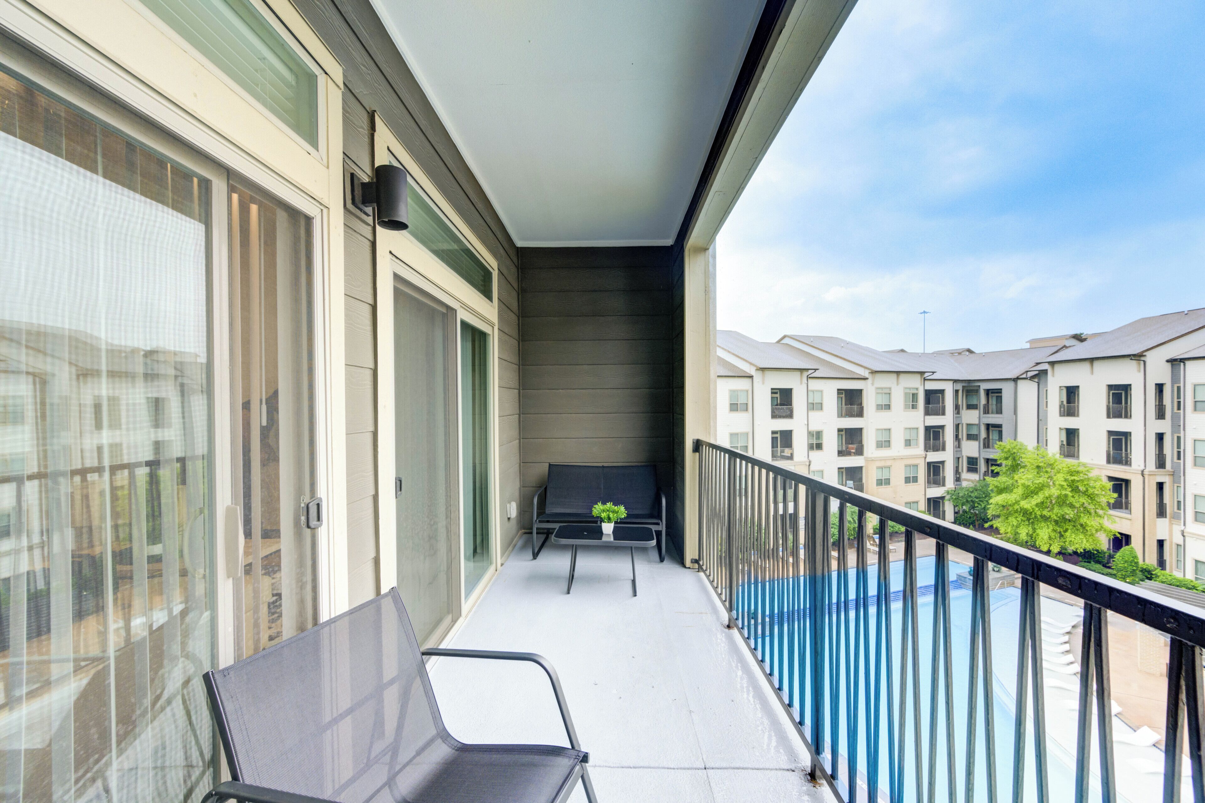 A balcony with a chair, a small table, and a potted plant.
