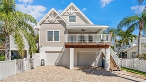 A two-story house with a balcony, a garage, and a staircase leading to the second floor. - Pool - The Sea Pearl by SeaBreeze Vacation (Holmes Beach)