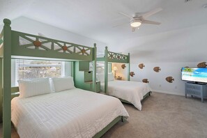 A bedroom with two beds, a ceiling fan, and a TV on the wall. - The Sea Pearl (Holmes Beach)