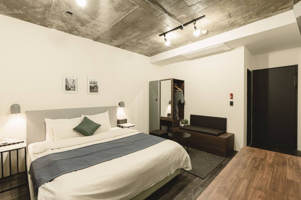 Ein modernes Hotelzimmer mit Bett, Nachttisch und Spiegel.