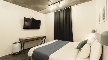 A modern bedroom with a bed, a desk, a TV, and a curtain.