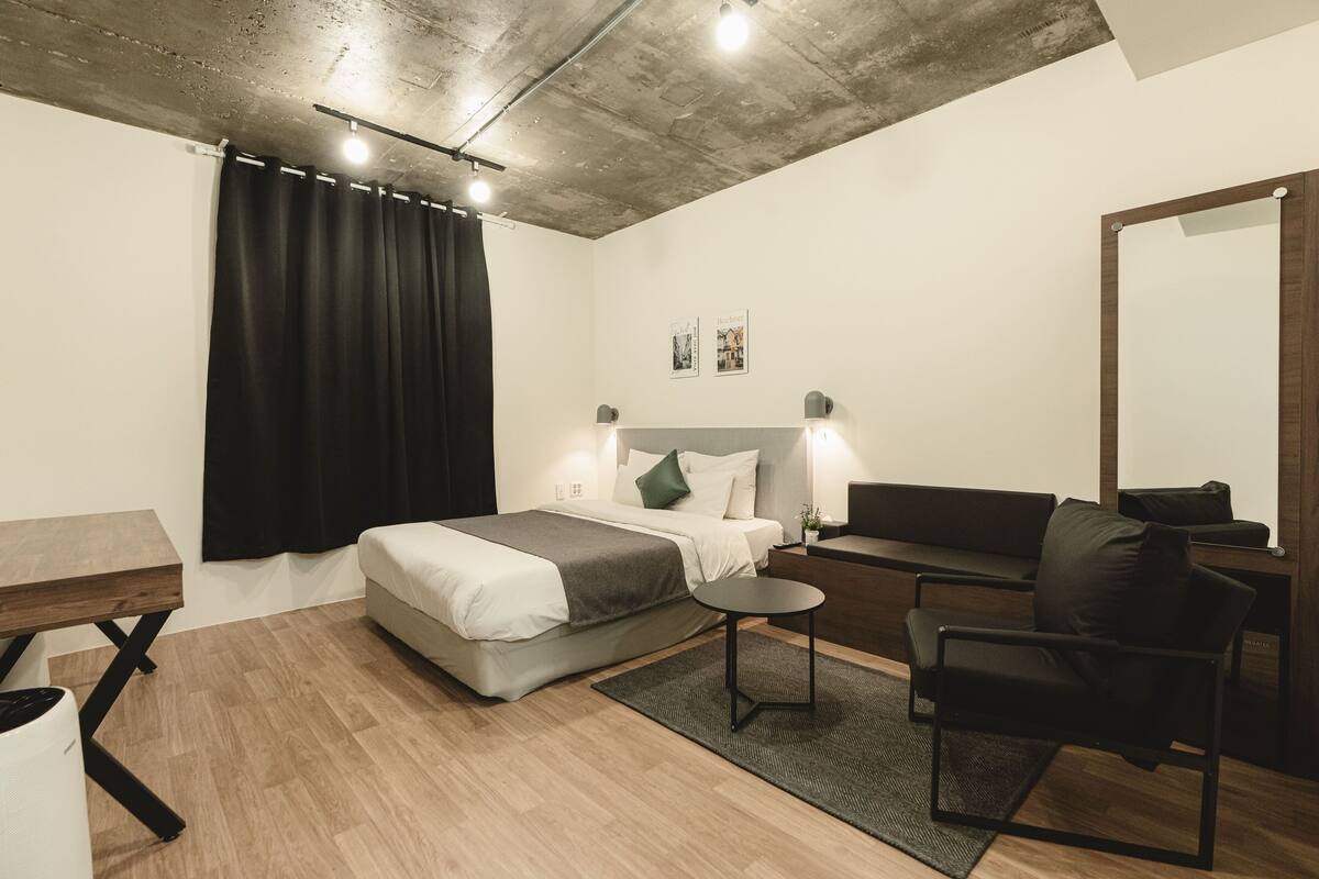 Ein modernes Schlafzimmer mit einem Bett, einem Schreibtisch, einem Stuhl, einem Spiegel und einer Deckenleuchte.