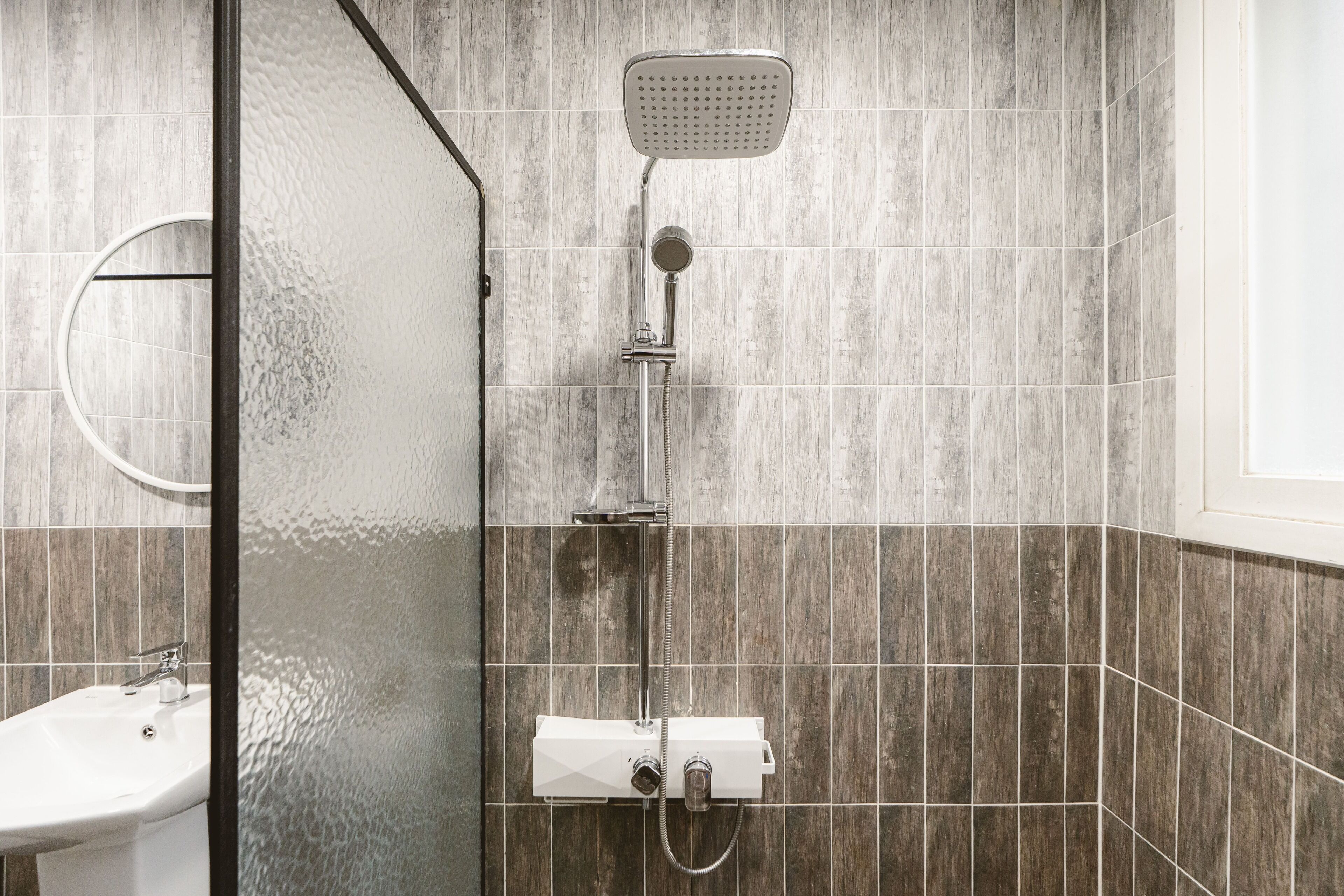 A modern bathroom with a shower, a sink, and a glass-enclosed shower area.
