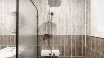 A modern bathroom with a shower, a sink, and a glass-enclosed shower area.
