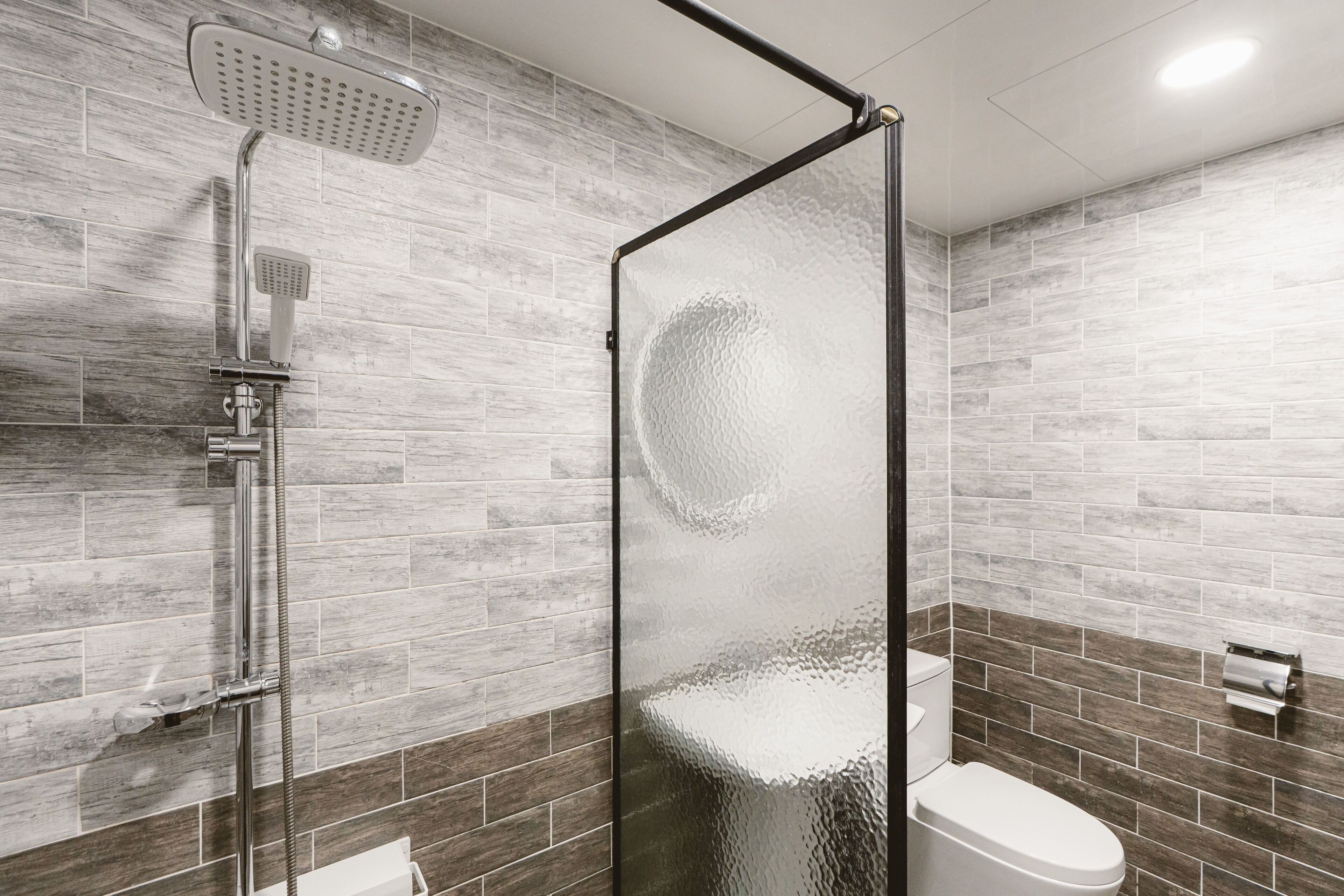 Een moderne badkamer met een douchecabine van glas, een toilet en een handdoekrek.