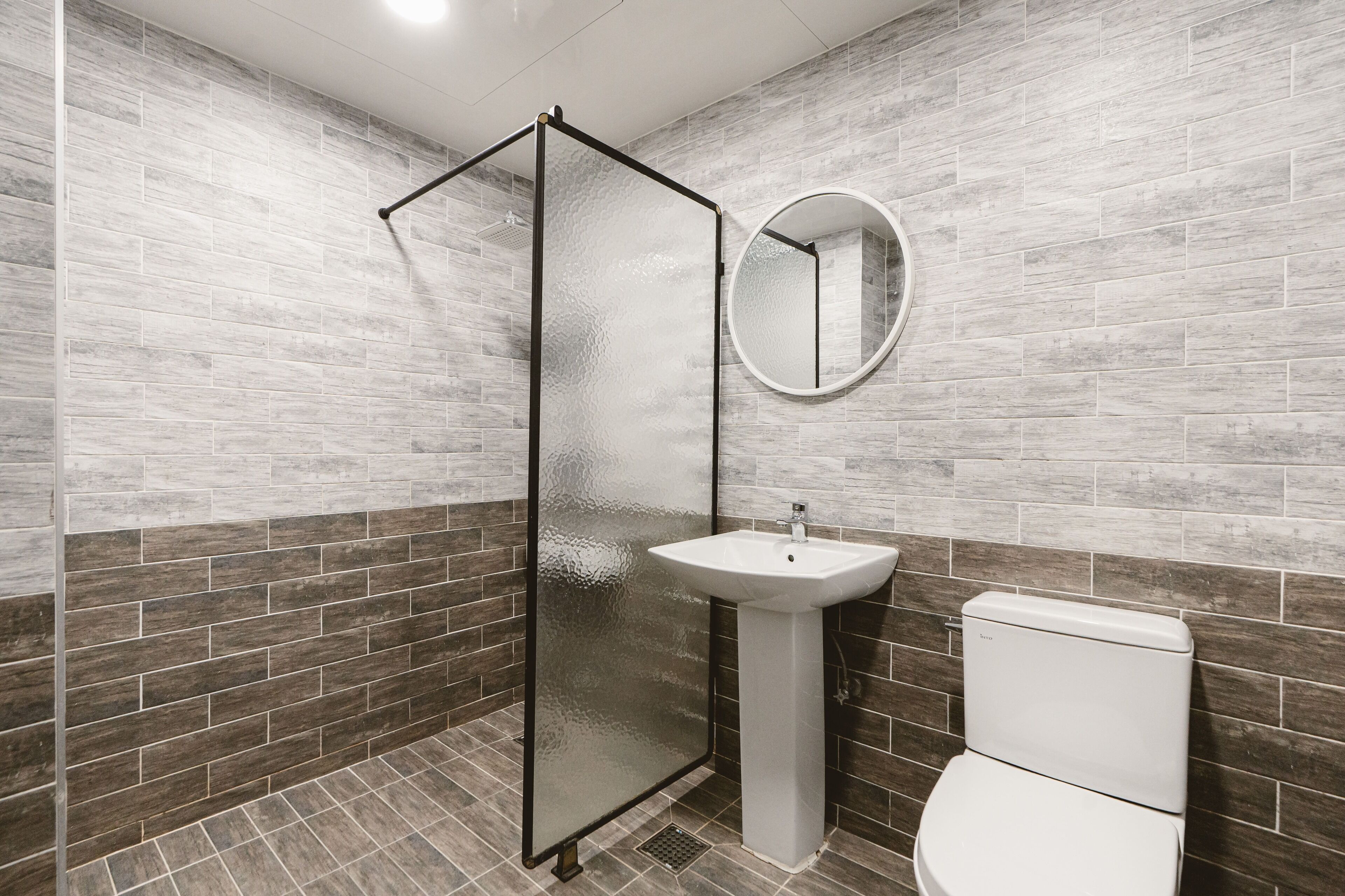 Un baño con cabina de ducha de vidrio, un lavamanos pedestal y un inodoro.