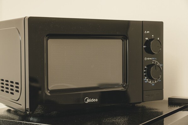 A black Midea microwave oven with a digital display and control knobs. - Hotel Solide Cheonan (Cheonan)