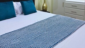 Una habitación de hotel con cama, mesita de noche, lámpara, armario y espejo.