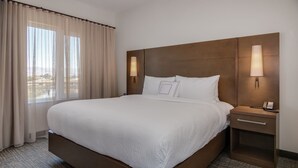 Habitació d'hotel amb un llit gran, dues taules de nit i una finestra amb cortines.