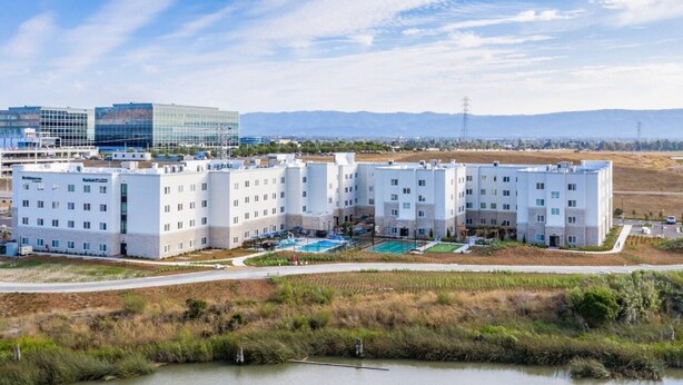 Un complex hoteler modern amb diversos edificis, una piscina i un paisatge natural circumdant.