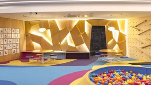 Una sala giochi con pareti colorate, una piscina di palline e diversi tavoli da gioco.