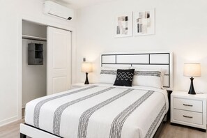 A bedroom with a bed, bedside tables, a wardrobe, and two wall-mounted artworks. - Elegant Stay • Downtown • Steps to Convention Ctr (Hot Springs)