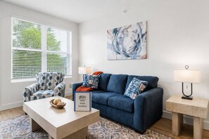 En moderne stue med en blå sofa, en lænestol med et mønster og et sofabord med dekorative genstande.