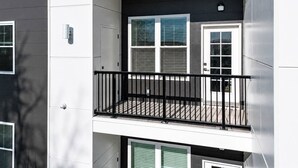 A multi-story building with a balcony on the second floor, featuring a black railing and a door with a window. - Elegant Stay • Downtown • Steps to Convention Ctr (Hot Springs)