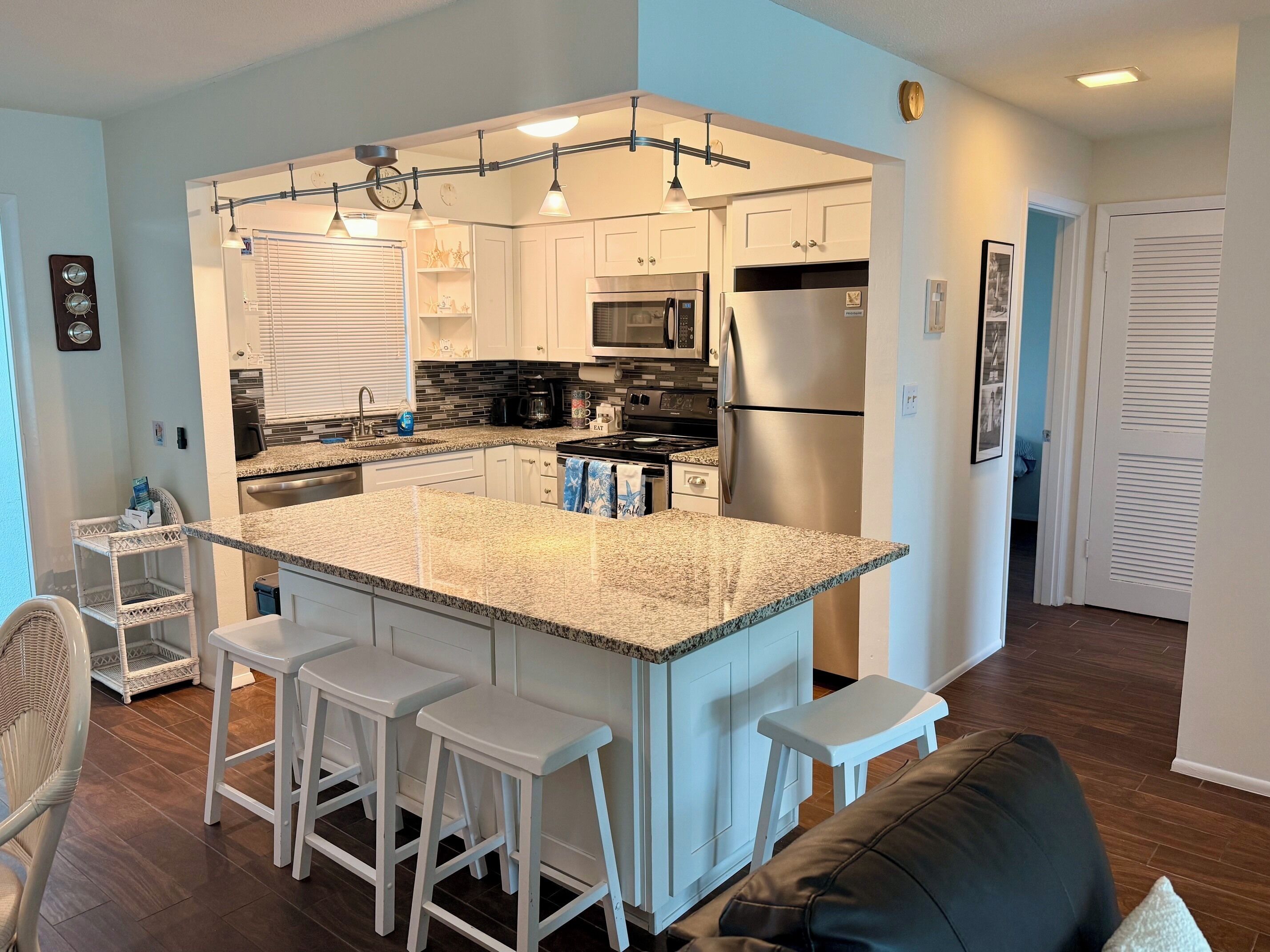 A modern kitchen with a central island, bar stools, and a refrigerator.