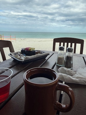 A table with a mug, salt and pepper shakers, a tray with condiments, and a drink. - 2 Bed Condo w/pool right on Bradenton Beach! Walk to Everything! (Bradenton Beach)