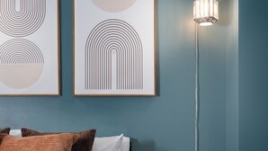 A bedroom with a bed, pillows, a nightstand, a lamp, and two framed artworks on the wall.