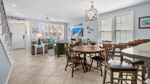 A spacious living area with a dining table, chairs, and a kitchen area. - Ocean View Surfside House w/ Pool & Walk to Bars (Surfside Beach)