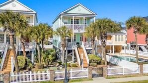 A beachfront property with a two-story house, a swimming pool, and a white picket fence. - Ocean View Surfside House w/ Pool & Walk to Bars (Surfside Beach)