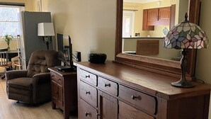 Un salon avec un meuble en bois, un canapé, une lampe et un grand miroir.