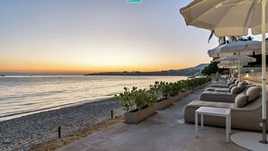 A beachfront seating area with planters, a poolside lounge, and umbrellas. - 4BR Hidden Gem: Luxe Oceanfront Living in Bucerias (Bucerías)
