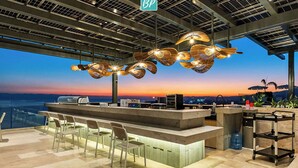 A modern bar area with a view of the sunset, a large water dispenser, and a BP sign. - 4BR Hidden Gem: Luxe Oceanfront Living in Bucerias (Bucerías)
