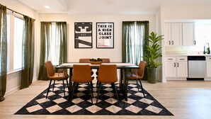 A dining area with a table, chairs, and a black and white rug. There are two framed pictures on the wall and a potted plant. - Retro-Luxury 3BR/2BA Home-Minutes from Downtown and Houston hot spots (Houston)
