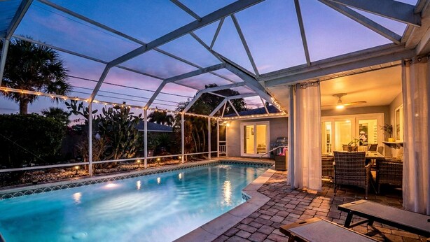 Ein Pool mit überdachter Terrasse, inklusive Sitzgelegenheiten und Essbereich.