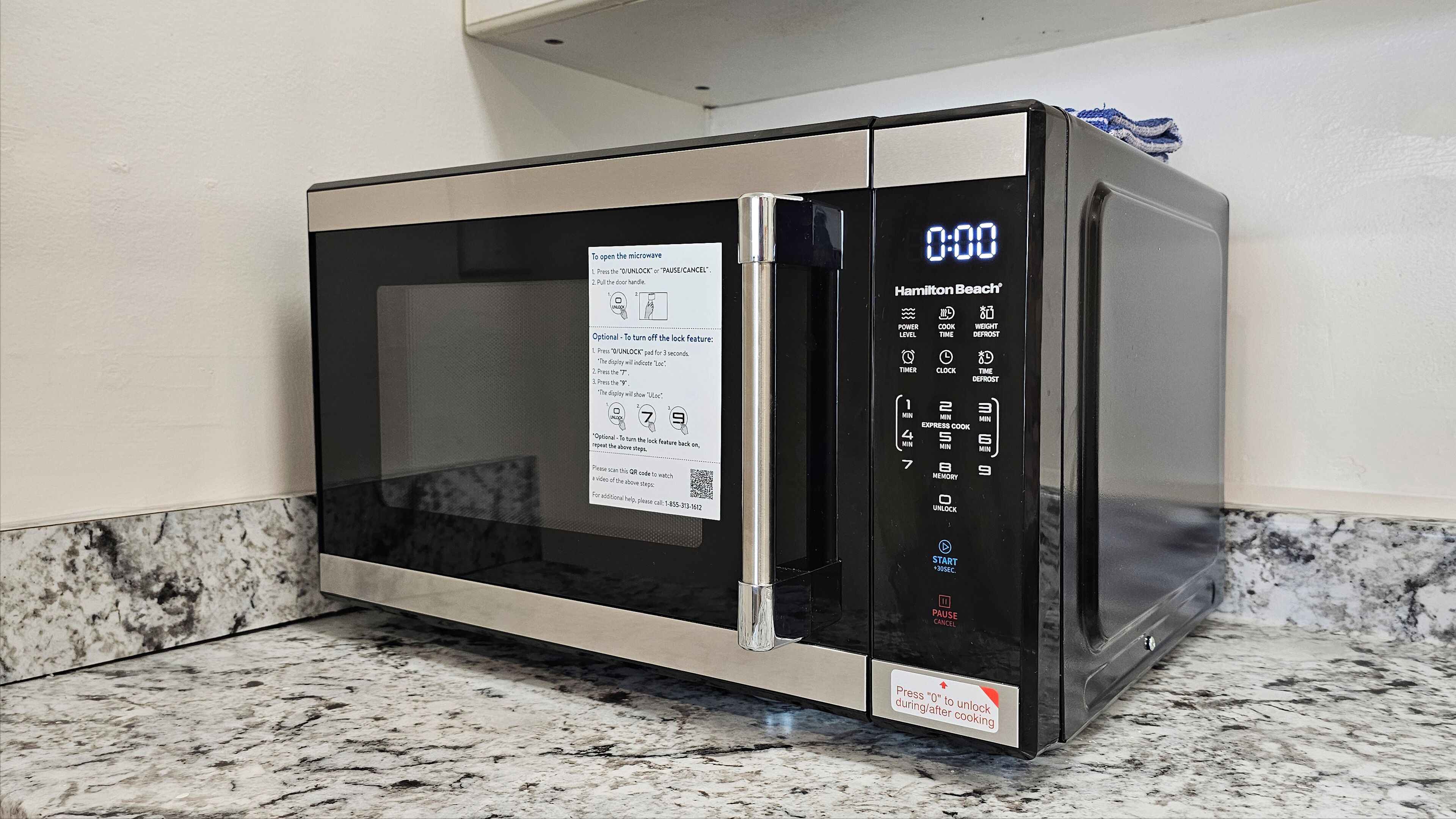 A microwave with a digital display and a QR code for additional instructions.
