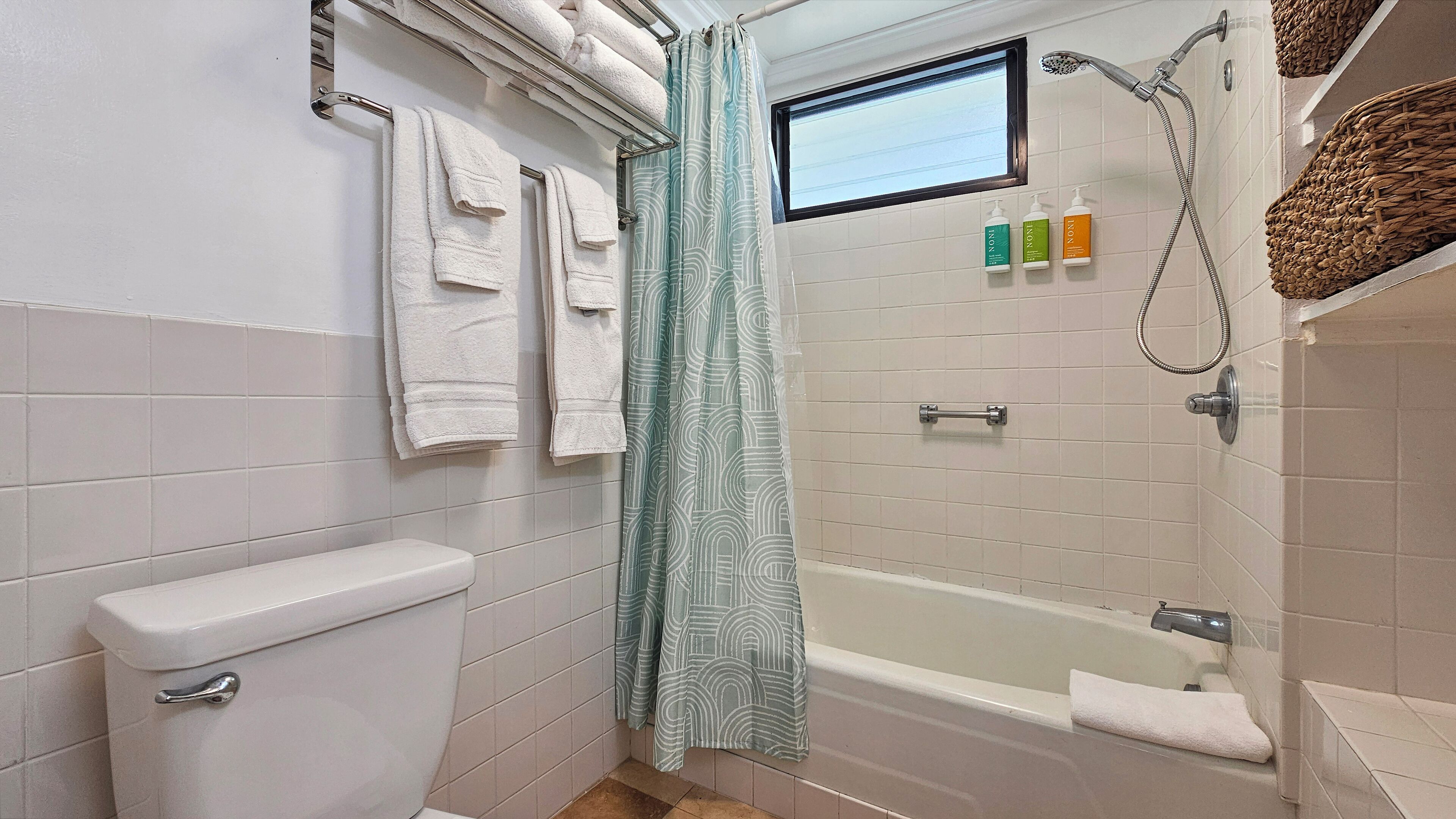 A bathroom with a toilet, a bathtub, a shower, and a window.