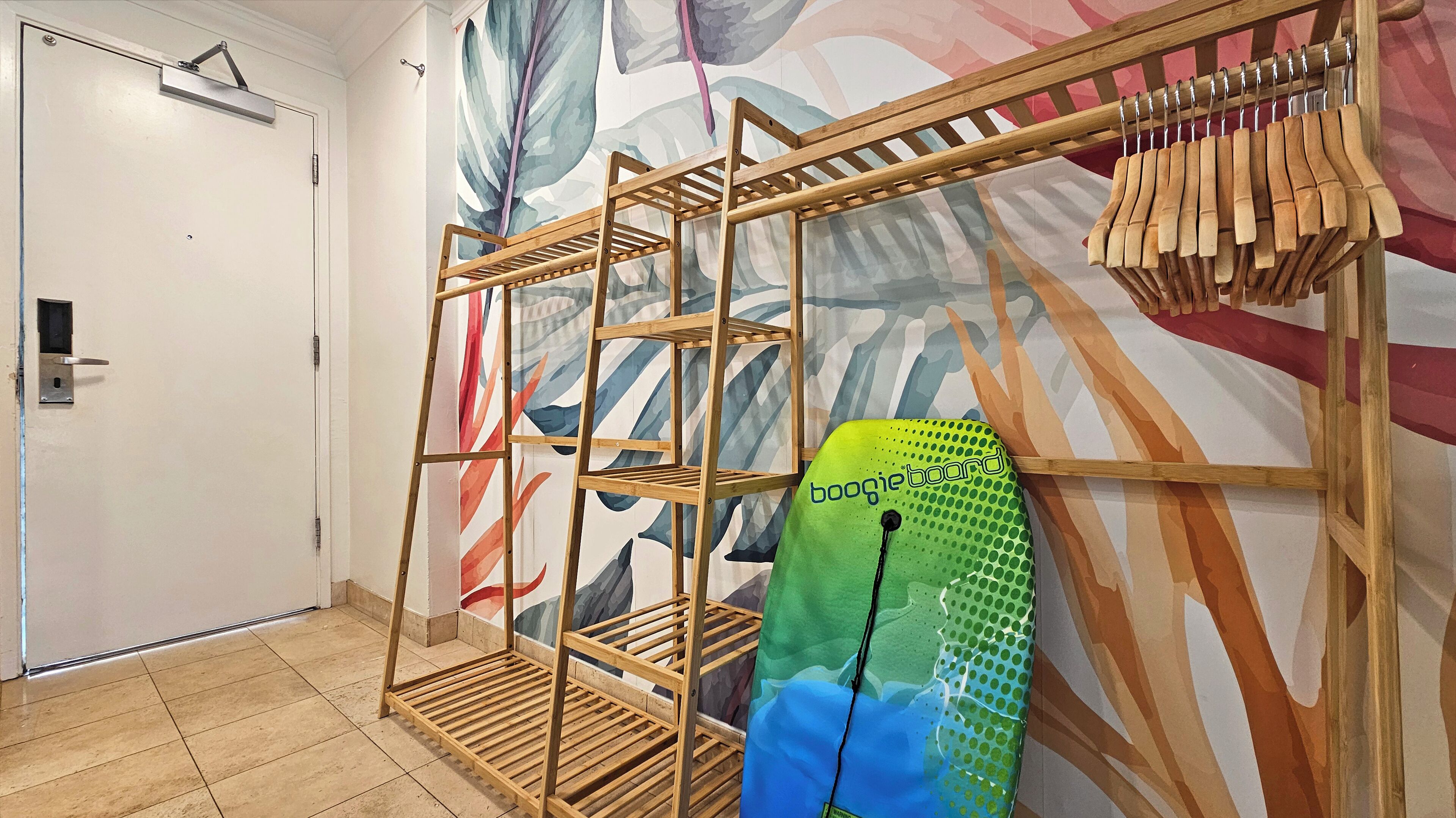 A room with a wooden rack holding clothes, a surfboard, and a door with a handle.