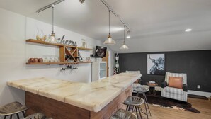 Een moderne keuken met een marmeren eiland, barstoelen en hanglampen.