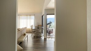 A spacious living area with a high ceiling, a sofa, a dining table with chairs, and a telescope on a balcony. - Naci Vista Retreat - Incredible Lake Views (Bradley)
