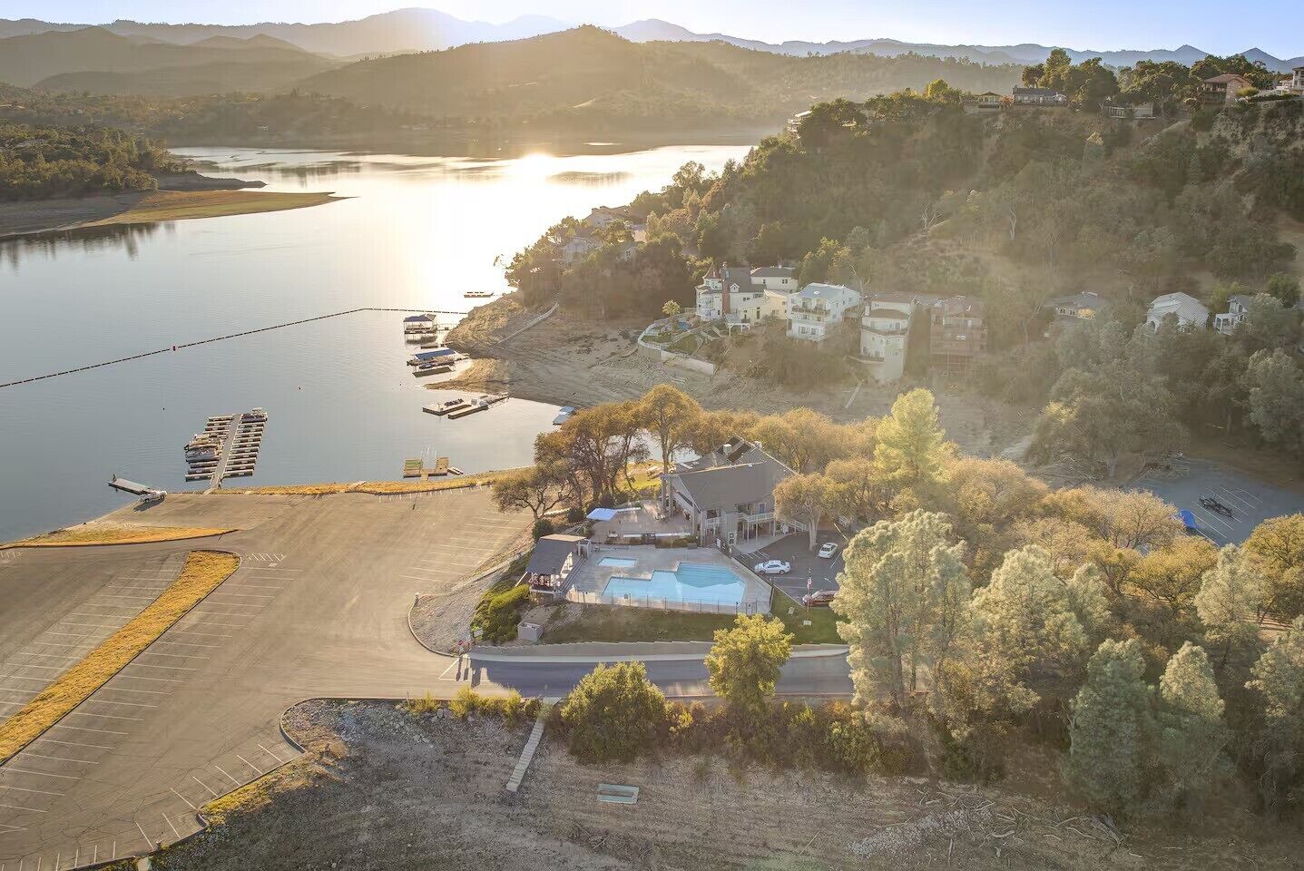 Une propriété au bord du lac, dotée d’une piscine, d’un quai et d’un bâtiment avec une grande fenêtre donnant sur l’eau.