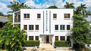 Un edificio blanco con el nombre "BROADVIEW" en el centro, rodeado de vegetación y un cielo despejado.