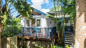 A white house with a blue roof, surrounded by tropical vegetation.