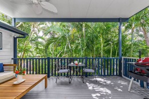 A covered outdoor area with a wooden deck, two chairs, a table, and a grill. - Broadview`s Secret Hideaway (Brunswick Heads)