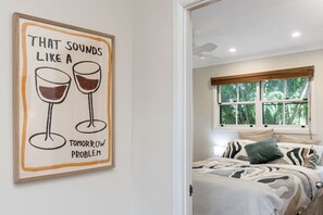 A bedroom with a bed, pillows, a window with a view of trees, and a wall with a framed poster. - Broadview`s Secret Hideaway (Brunswick Heads)