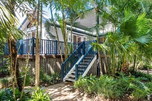 A tropical garden with a wooden deck and blue railing leading to a house. - Broadview`s Secret Hideaway (Brunswick Heads)
