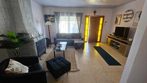 Een woonkamer met een bank, een salontafel, een televisie en een open haard.