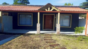 Une maison avec un toit en tuiles, une porte d’entrée et deux fenêtres avec des barreaux.