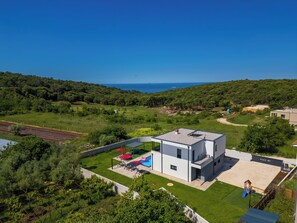 Ein modernes Haus mit Pool, Terrasse und Meerblick.