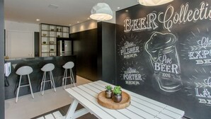 A modern kitchen with a black backsplash, white bar stools, and pendant lighting. - Sambadrome | Allianz Parque | Expo Center Norte | Bom Retiro. (São Paulo)